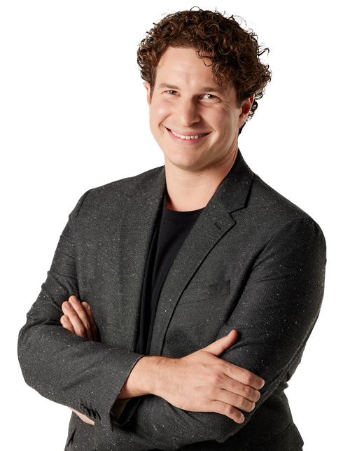 trade show magician Evan Northrup wearing a gray sport coat and black shirt, smiling with arms folded