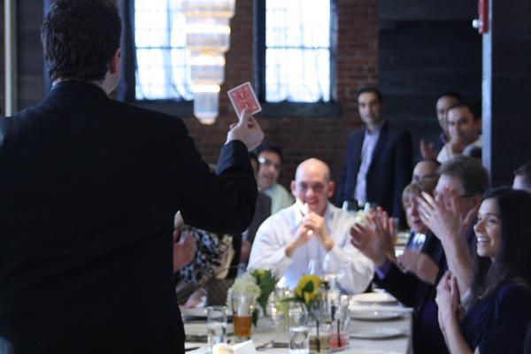 Evan performing for a corporate dinner audience, card reveal with guests applauding