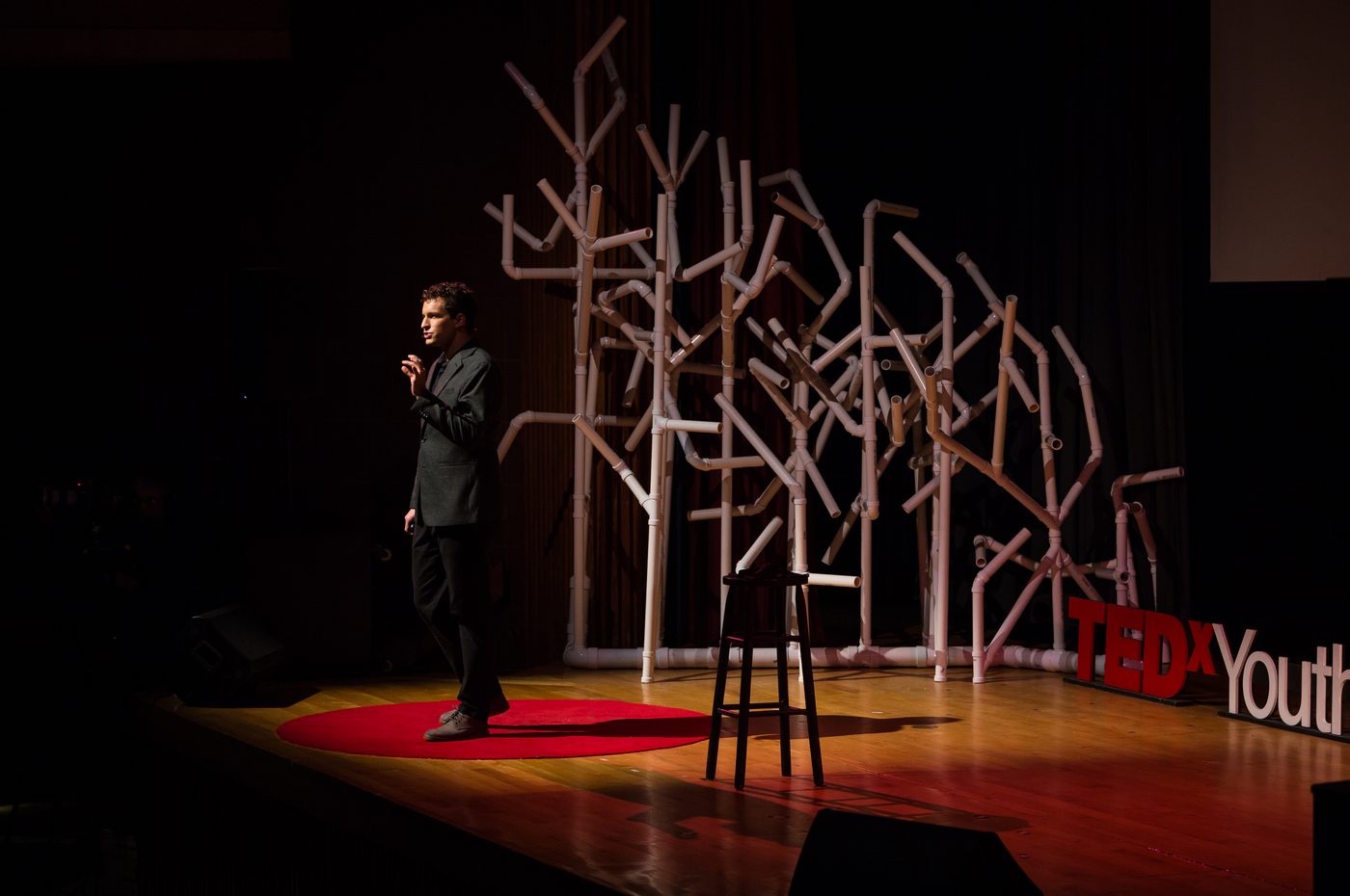 Evan Northrup on the TEDx stage, wide shot with TEDxYouth letters and backdrop