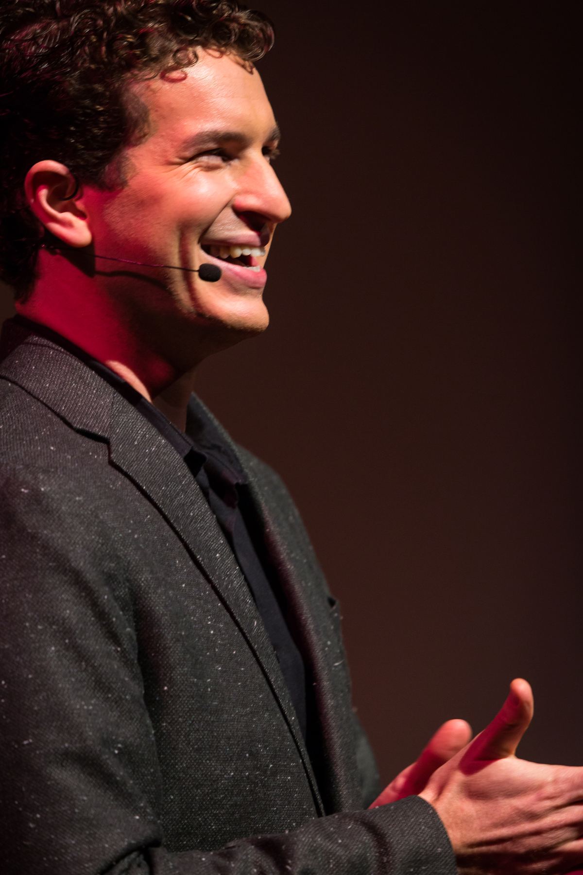 Evan Northrup smiling on stage with headset mic, keynote speaker and experience designer